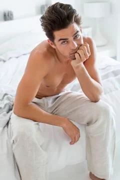 Serious man sitting on the bed Stock Photos