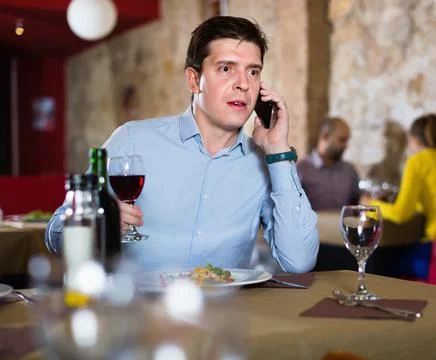 Serious man solving problems on phone while dining in restaurant Stock Photos
