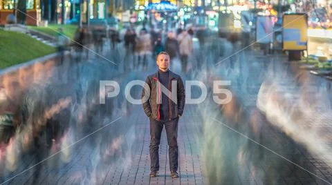 The serious man stand in the ghost-like crowd stream. Evening - night time,.. Stock Photos