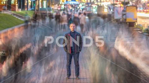 The serious man stand in the ghost-like crowd stream. Evening - night time,.. Stock Photos