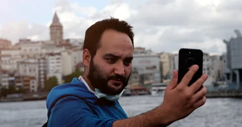 A serious man taking a selfie in front of Galata Tower in Istanbul, Turkey Видео 162022678