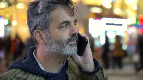 Serious man talking on smart cell phone on busy city street. New York setting Stock Photos
