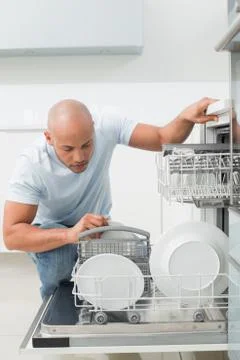 Serious man using dish washer in kitchen Stock Photos