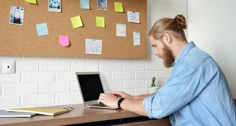 Serious man using laptop working or studying from home sitting at office desk. Stockfoto's