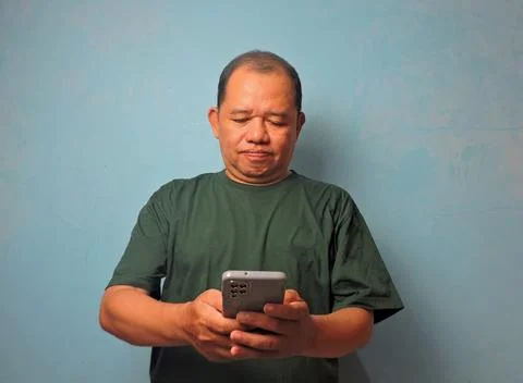 Serious Man Using Smartphone Against Blue Wall Stock Photos