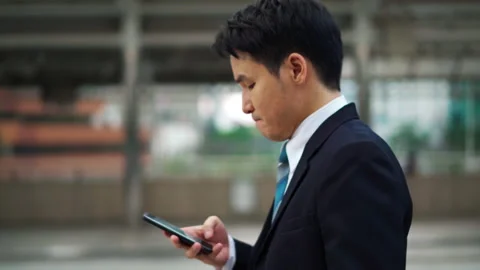 Serious man walking and using a smartphone in the city Stock Footage 141734627