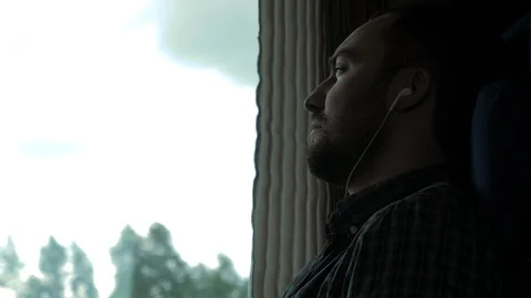 Serious man by the window on the train listening to music. Vidéo 115982925