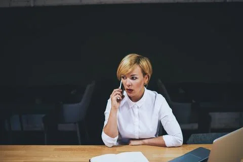 Serious manager talking on smartphone while working in office Stock Photos