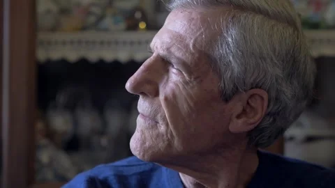 Serious mature gray haired man turns from window toward camera indoors 库存影片 334776252