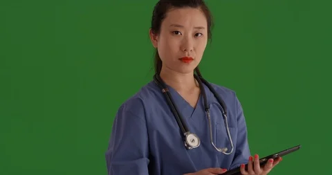 Serious medical assistant posing with tablet pc on greenscreen Vídeos de archivo 85493977