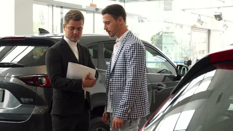 Serious men finalize a car purchase agreement in a sleek dealership Stock Footage 311987883