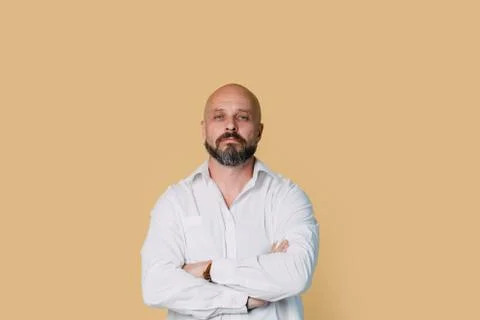 Serious middle-aged man with folded arms and a deadpan expression posing in f Stock Photos