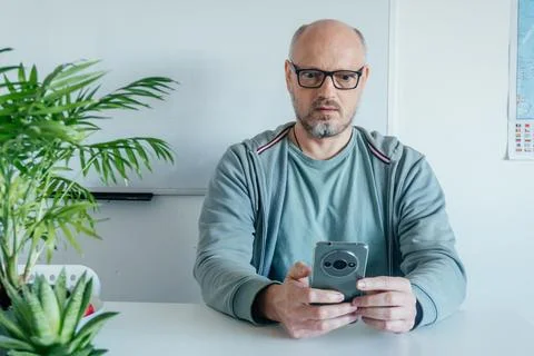 Serious Middle Aged Man Sitting At Desk With Coffee Foto stock