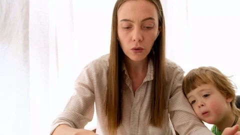 Serious mother with son trying to work from home Stock Footage 128285745