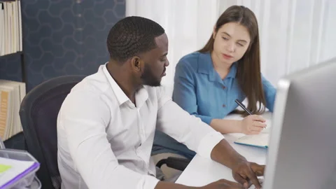 Serious multi-ethnic young man and woman working together in business office. Stock Footage 228806391