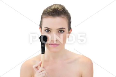Serious natural brown haired model holding a blush brush Stock Photos