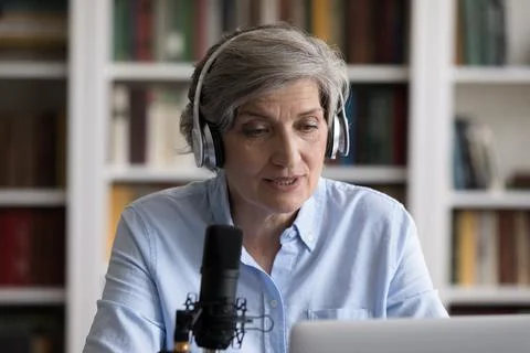 Serious newscaster, radio host in headphones speaking at professional microphone Stock Photos