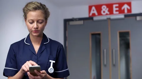 Serious nurse using cell mobile phone in front of doors in hospital Stock Footage 59087324