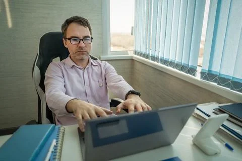 Serious office worker using laptop at desk, focused on online work, business  Stock Photos
