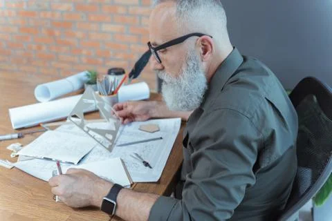 Serious old engineer is correcting building plan Foto stock