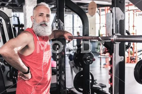 Serious old male is standing in modern athletic center Stock Photos