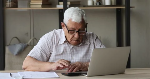 Serious older man using calculator and laptop makes online payments Stock Footage 170658166