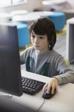 Serious pre-adolescent boy using computer in classroom Stock Photos