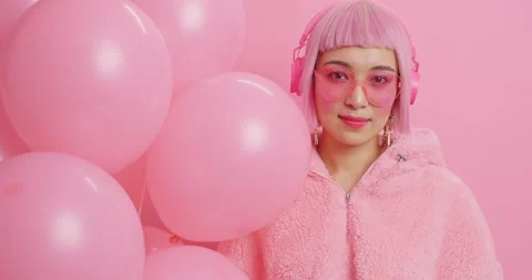 Serious pretty pink haired young woman with eastern appearance looks directly at Stock Footage 147522685