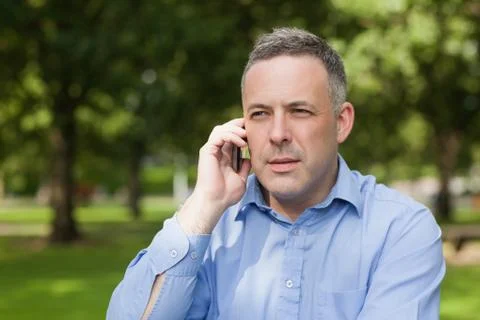 Serious professor calling on phone while sitting on bench on campus Fotos Stock