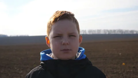 Serious red-haired boy looks into camera against the blurred background Stock Footage 324826236