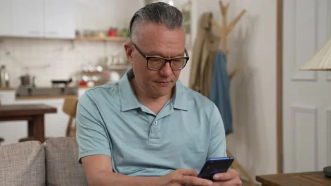 Serious retired man using mobile phone at home Stock Footage 204786477