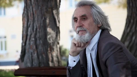 A serious sad gray-haired man with a beard in a suit thinks about a problem Stock-Footage 96503109