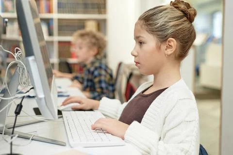 Serious Schoolgirl using Computer in Library 库存照片