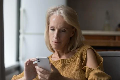 Serious senior elder lady using online app on smartphone Stock Photos