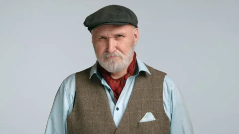 Serious Senior Man in Flat Cap and Tweed Vest on Grey Background Stock Footage 262858932
