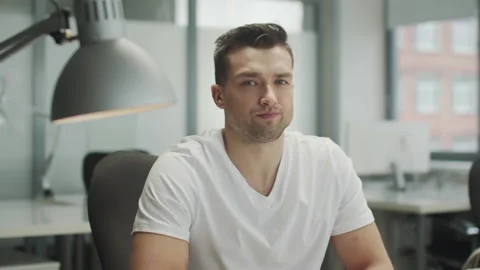 A serious, strict young man in a white T-shirt in the interior of an openoffice Video stock 150334588