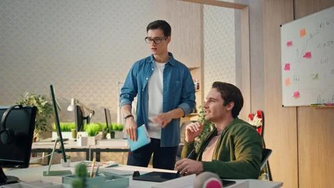 Serious teammates working computer at office. Man staring monitor drawing tablet Stock Photos