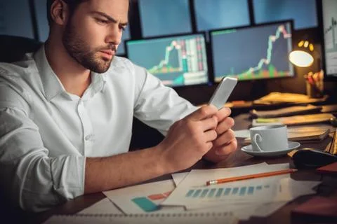 Serious trader using mobile app on smartphone for data analysis Stock Photos