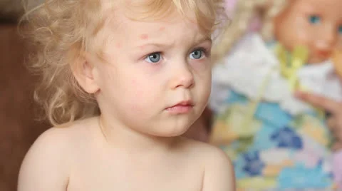 Serious two years old curly hair baby girl watching tv at home Stockbeeldmateriaal 24497725