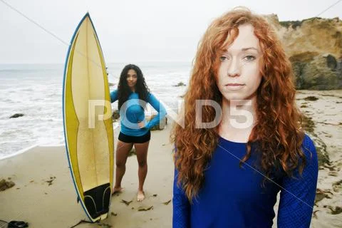 Serious women holding surfboards at beach Stock Photos