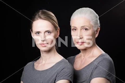 Serious women looking at camera, young and senior people isolated on black Stock Photos