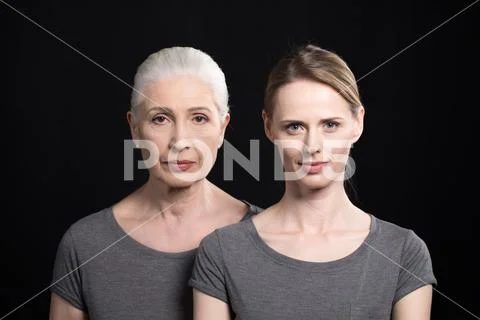 Serious women looking at camera, young and senior people isolated on black Stock Photos