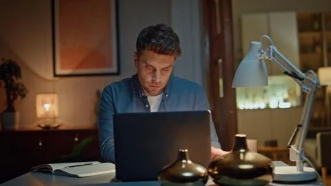 Serious worker checking phone sms in late interior closeup. Man typing laptop Stock Photos