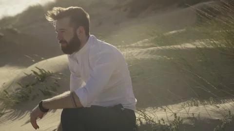 Serious yang man sitting in desert Stock Footage 87146008