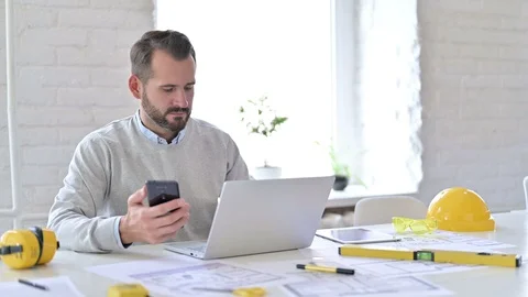 Serious Young Architect using Smartphone in Office Stock Footage 127597009