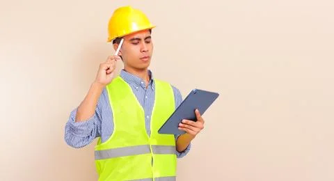 Serious young Asian construction worker wearing safety vest and hard hat us.. Stock Photos