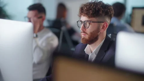 Serious Young Bearded Man Working on Decktop Computer While Working in Big Open Stock Footage 168645052