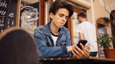 Serious young boy sitting in cafe use phone drink juice portrait close up Stock Footage 92052601