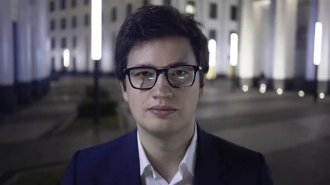 Serious young businessman looking to the camera, night city 動画素材 83523731