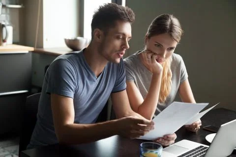 Serious young couple checking documents with using laptop Fotos de archivo